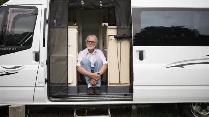 ein ältere MAnn sitzte in seinem Minicamper