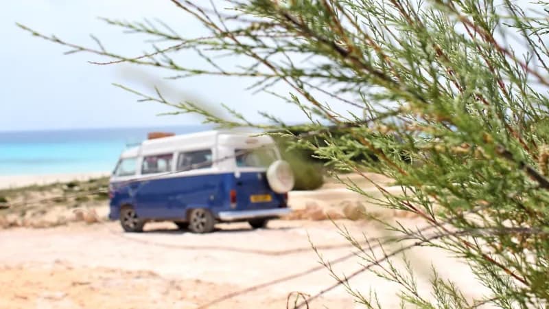 ein alter Minicamper steht am Strand